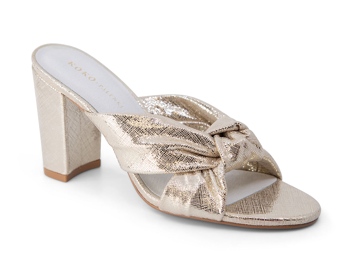 Gold high-heeled sandal with a bow on a white background