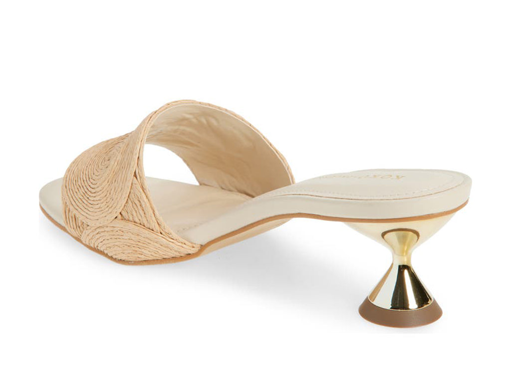 Slide sandal with a gold flared heel and one strap circle pattern raffia upper- view of the gold flared heel 